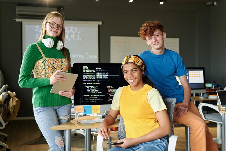 Foto retrato de un grupo de estudiantes sonriendo a la cámara mientras trabajan en equipo en una lección de ti