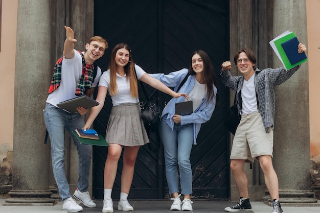 Retrato de grupo de estudiantes sonrientes multirraciales con libros y mochilas mirando a la cámara Concepto de educación