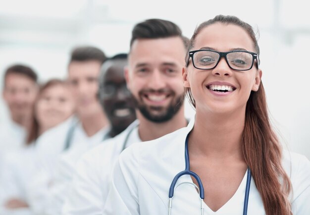 Retrato del grupo feliz confiado de doctores que se colocan en la oficina médica