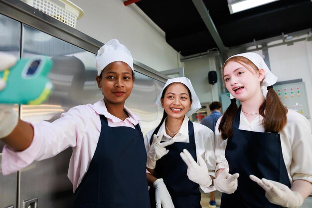 Retrato de grupo joven adolescente cocinera estudiante Clase de cocina aula culinaria joven feliz tomando foto selfie por teléfono inteligente en la escuela de cocina