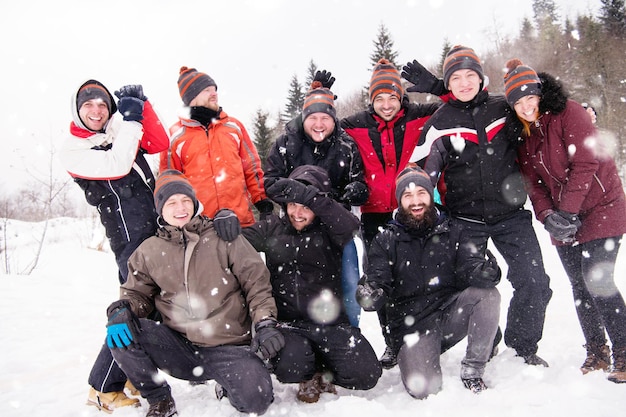 retrato de grupo de jóvenes empresarios felices disfrutando de un día de invierno nevado con copos de nieve a su alrededor durante un trabajo en equipo en el bosque de montaña