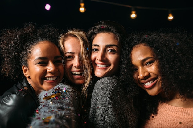 Retrato de un grupo de mujeres diversas sonriendo y mirando la cámara por la noche