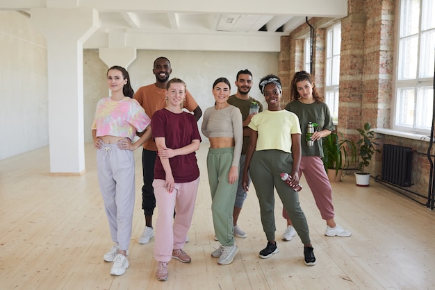 Retrato de grupo multiétnico de bailarines sonriendo mientras está de pie en el estudio de danza