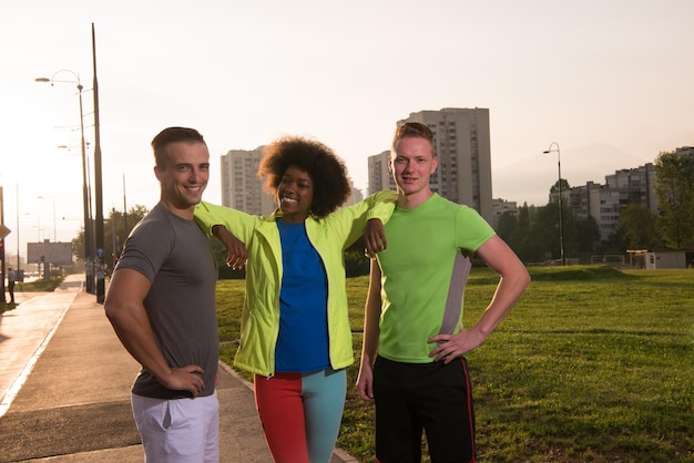 Retrato de un grupo multiétnico de jóvenes en la hermosa noche de verano para correr mientras el sol se pone sobre la ciudad