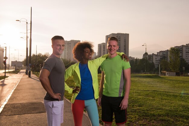 Retrato de un grupo multiétnico de jóvenes en la hermosa noche de verano para correr mientras el sol se pone sobre la ciudad