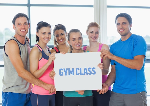 Retrato de un grupo de personas felices sosteniendo carteles en blanco en el gimnasio