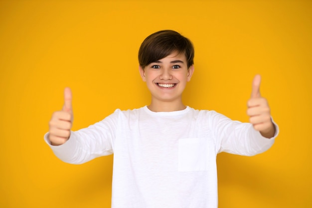 Retrato de un guapo adolescente de 12 a 13 años sobre un fondo amarillo.