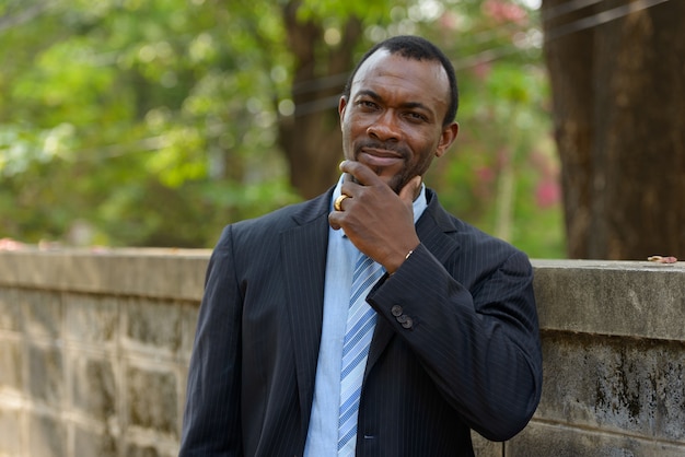 Retrato de guapo empresario africano barbudo en las calles al aire libre