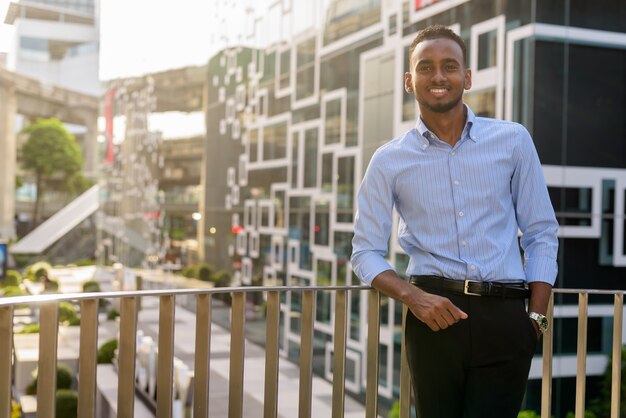 Retrato de guapo empresario africano negro al aire libre en la ciudad durante el verano