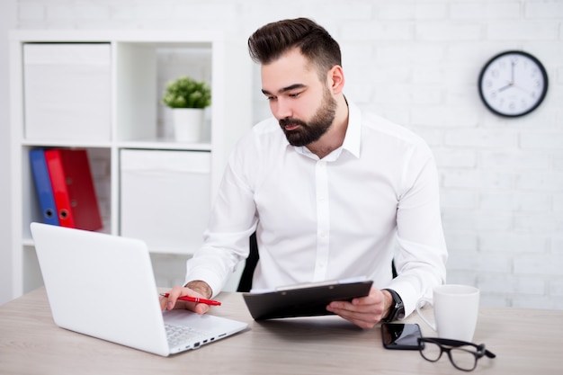 Retrato de guapo empresario barbudo que trabaja en la oficina moderna