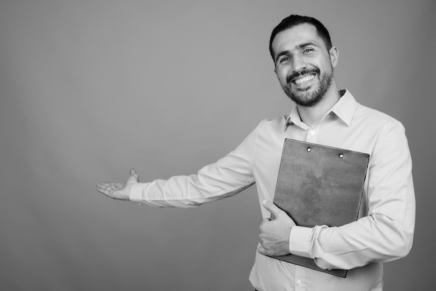 Retrato de guapo empresario persa barbudo en gris en blanco y negro