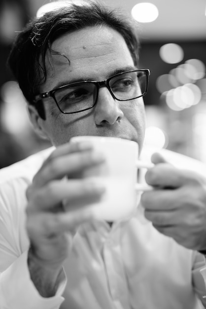 Retrato de guapo empresario persa relajante en la cafetería en blanco y negro