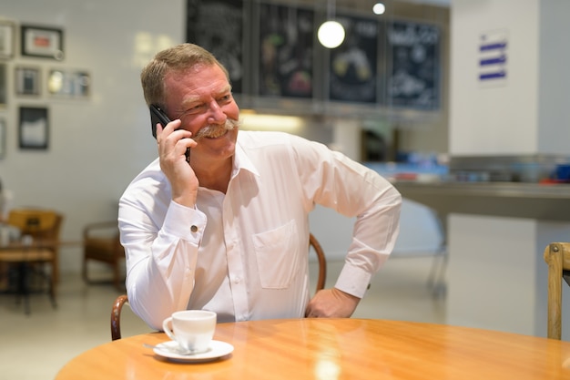 Retrato de guapo empresario senior con bigote en la cafetería.