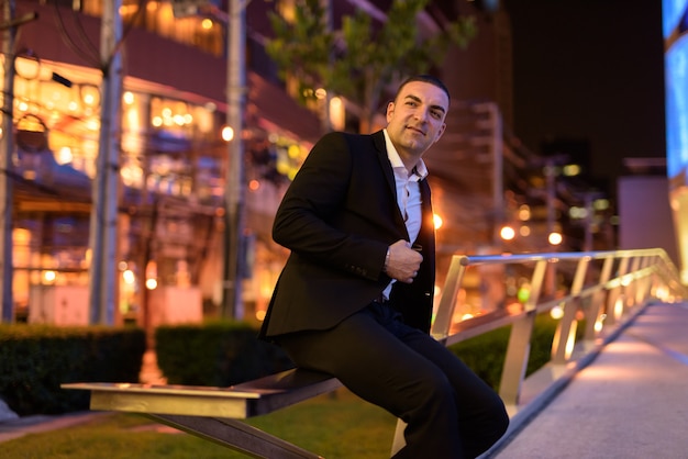 Retrato de guapo empresario vistiendo traje al aire libre por la noche en la ciudad