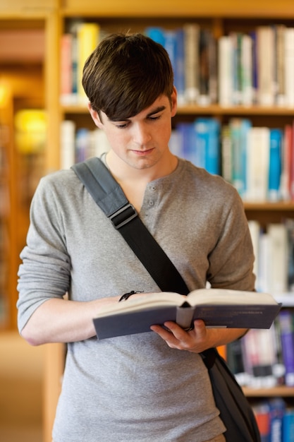 Retrato de un guapo estudiante leyendo un libro