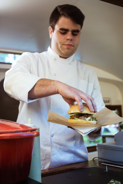 Retrato de guapo joven chef preparando albóndigas en un camión de comida en el parque.