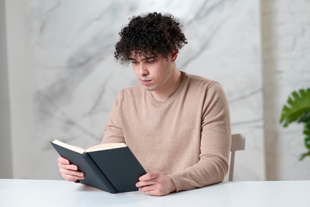 Retrato de guapo joven estudiante de tipo serio étnico concentrado lector inteligente está leyendo