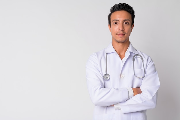 Retrato de guapo médico hispano contra la pared blanca