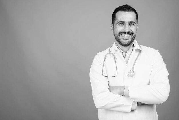 Retrato de guapo médico persa barbudo en gris en blanco y negro