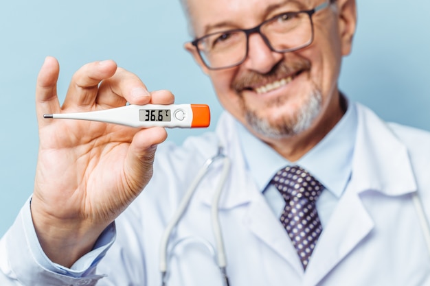 Retrato de un guapo médico senior con un termómetro en sus manos