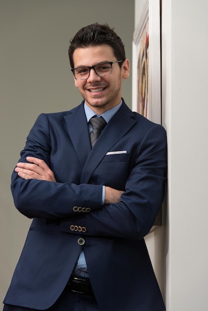 Foto retrato, de, guapo, seguro, joven, hombre de negocios, posición, armamentos cruzaron