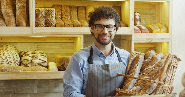 Retrato de guapo sonriente panadero trabajando en panadería