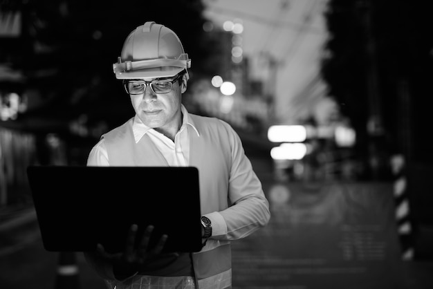 Retrato de guapo trabajador de la construcción persa en el sitio de construcción en blanco y negro