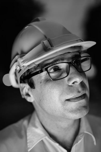 Retrato de guapo trabajador de la construcción persa en el sitio de construcción en blanco y negro