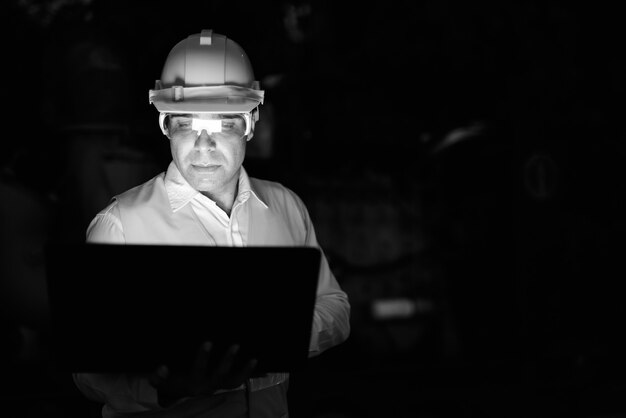 Retrato de guapo trabajador de la construcción persa en el sitio de construcción en blanco y negro