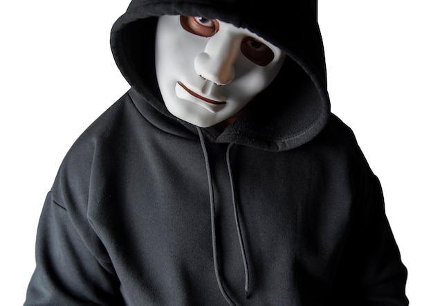 Un retrato de un hacker anónimo con una máscara y una capucha negra sentado con la cabeza inclinada y aterrador con un camino recortado Concepto de piratería y malware