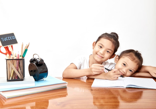 Foto retrato de hermanas sonrientes estudiando en la mesa en el hogar