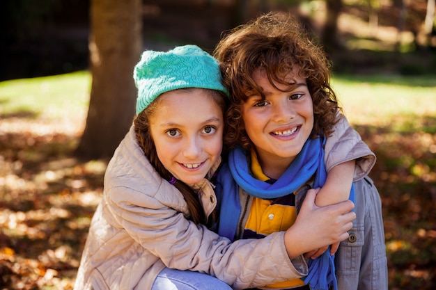 Retrato de hermanos felices abrazando en el parque