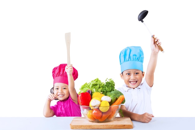 Foto retrato de hermanos sonrientes con comida en la mesa contra un fondo blanco