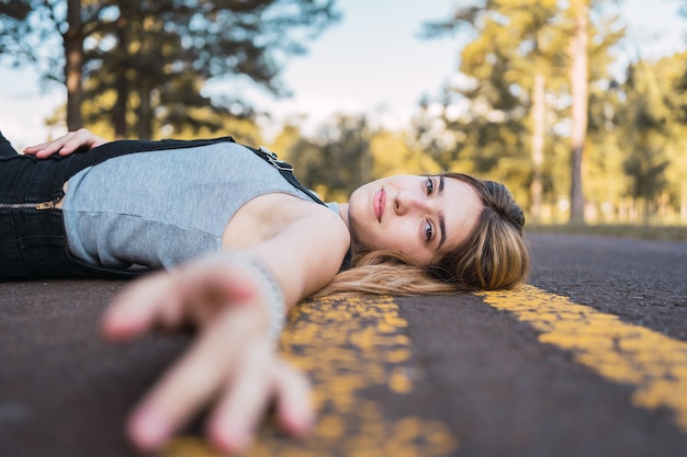 Retrato de una hermosa adolescente tirada en la carretera