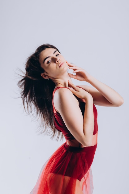 Retrato de una hermosa bailarina con un vestido rojo sobre un fondo blanco.