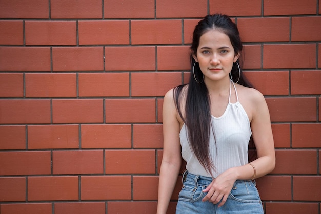 Retrato de hermosa chica asiática elegante posar para tomar una foto en el fondo de la pared Estilo de vida de la gente adolescente de Tailandia Concepto feliz de mujer moderna Estilo punk rock