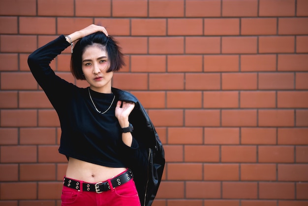 Retrato de hermosa chica asiática elegante posar para tomar una foto en el fondo de la pared Estilo de vida de la gente adolescente de Tailandia Concepto feliz de mujer moderna Estilo punk rock