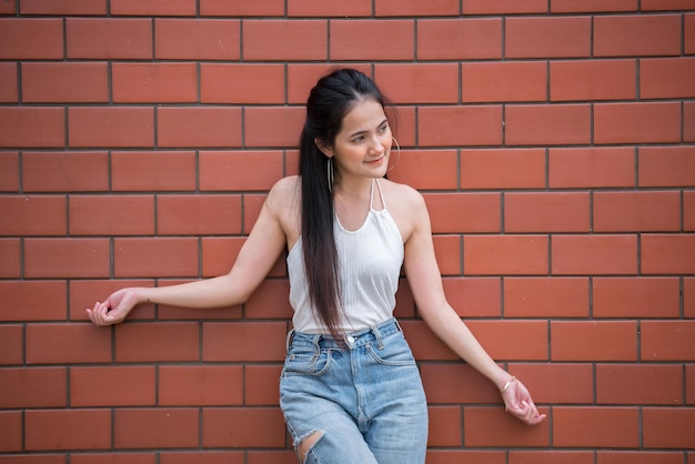 Retrato de hermosa chica asiática elegante posar para tomar una foto en el fondo de la pared de ladrillo Estilo de vida de la gente adolescente de Tailandia Concepto feliz de mujer moderna Estilo punk rock