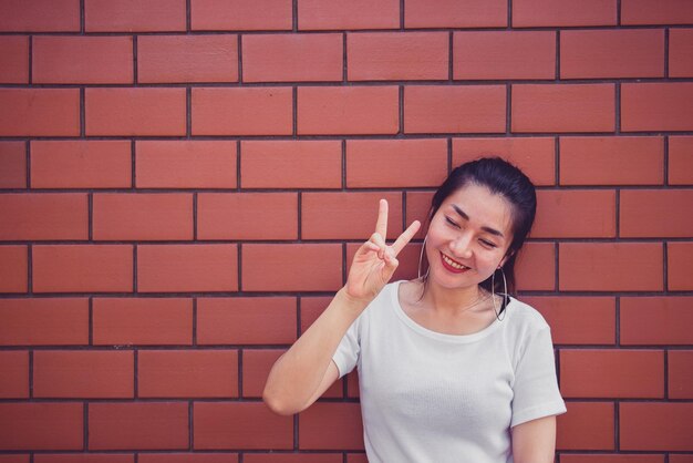 Retrato de hermosa chica asiática elegante posar para tomar una foto en la pared de ladrillosEstilo de vida de la gente adolescente de TailandiaConcepto feliz de mujer moderna