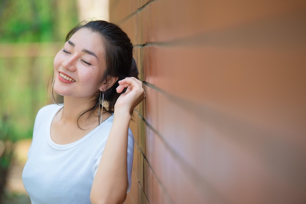 Retrato de hermosa chica asiática elegante posar para tomar una foto en la pared de ladrillosEstilo de vida de la gente adolescente de TailandiaConcepto feliz de mujer moderna