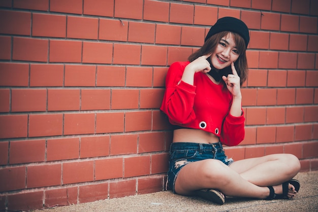 Retrato de una hermosa chica asiática elegante que usa un vestido negro para tomar una foto en una pared de ladrillos Estilo de vida de los adolescentes de Tailandia Concepto feliz de mujer moderna