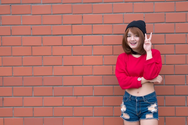 Retrato de una hermosa chica asiática elegante que usa un vestido negro para tomar una foto en una pared de ladrillos Estilo de vida de los adolescentes de Tailandia Concepto feliz de mujer moderna