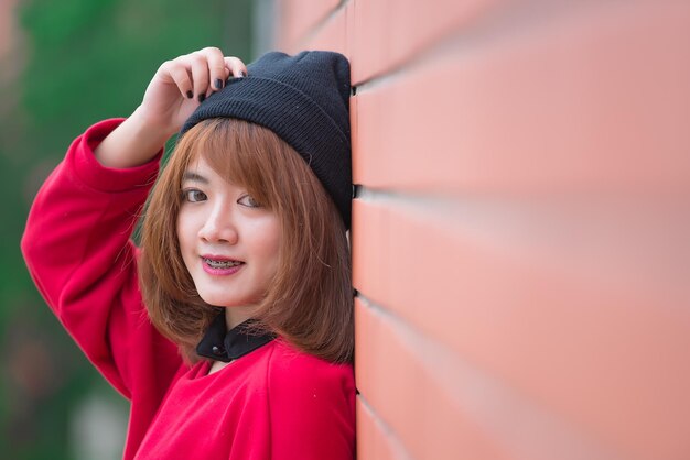 Retrato de una hermosa chica asiática elegante que usa un vestido negro para tomar una foto en una pared de ladrillos Estilo de vida de los adolescentes de Tailandia Concepto feliz de mujer moderna