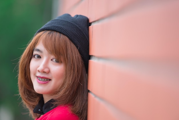 Retrato de una hermosa chica asiática elegante que usa un vestido negro para tomar una foto en una pared de ladrillos Estilo de vida de los adolescentes de Tailandia Concepto feliz de mujer moderna