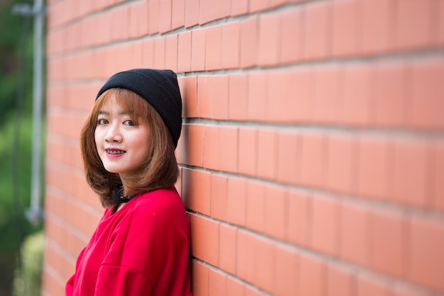 Retrato de una hermosa chica asiática elegante que usa un vestido negro para tomar una foto en una pared de ladrillos Estilo de vida de los adolescentes de Tailandia Concepto feliz de mujer moderna