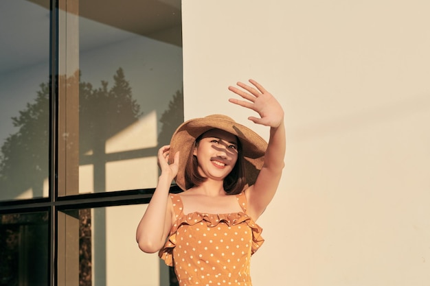 Retrato de una hermosa chica asiática que cubre la cara a mano de la luz del sol brillante felices vacaciones de verano