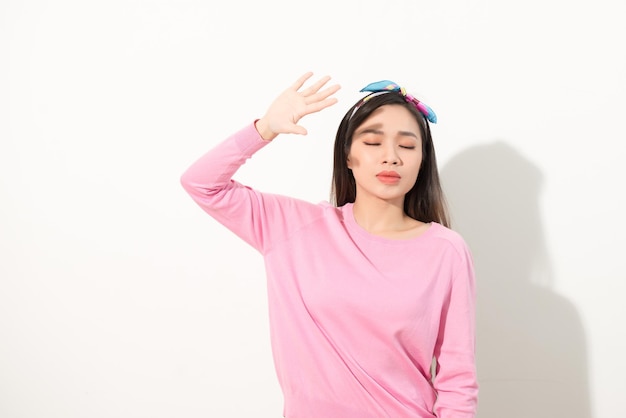 Retrato de una hermosa chica asiática que cubre la cara a mano de la luz del sol brillante. mujer con un vestido rosa que protege su rostro de la luz solar. Concepto de belleza o cuidado de la piel