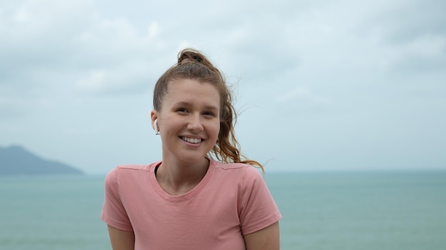 Retrato de una hermosa chica con auriculares en el fondo natural del océano o el mar en la montaña