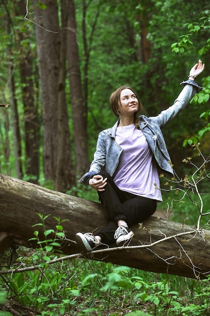 retrato de una hermosa chica en el bosque en los rayos del sol rompiendo los árboles