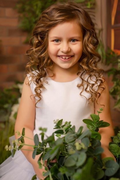 retrato de una hermosa chica de cabello castaño con un vestido blanco sobre un fondo de plantas y flores